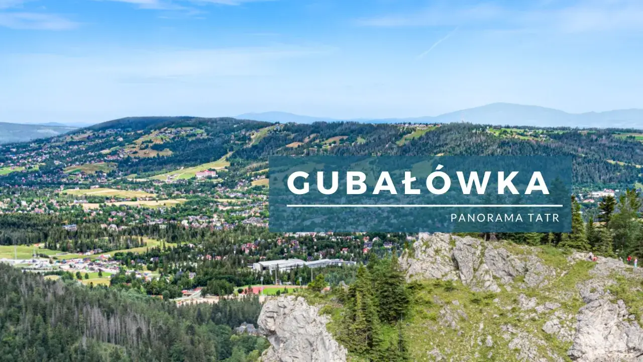 Widok z Gubałówki na rozległą panoramę Tatr i Zakopanego. W oddali góry, bliżej zielone wzgórza z zabudowaniami.