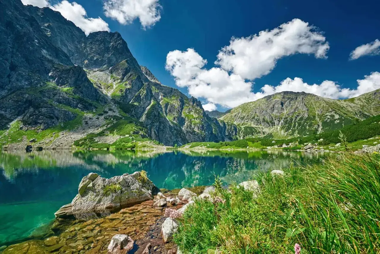 Wyprawa w g&oacute;ry nad krystalicznie czyste jezioro, otoczone skalistymi szczytami i zielenią.