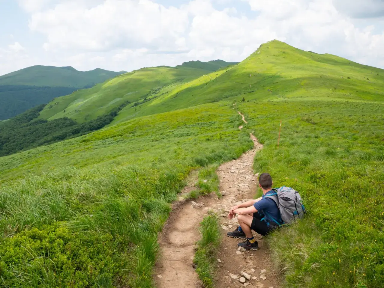 Bieszczady jakie to g&oacute;ry? Zielone połoniny, kręta ścieżka i turysta odpoczywający na szlaku.