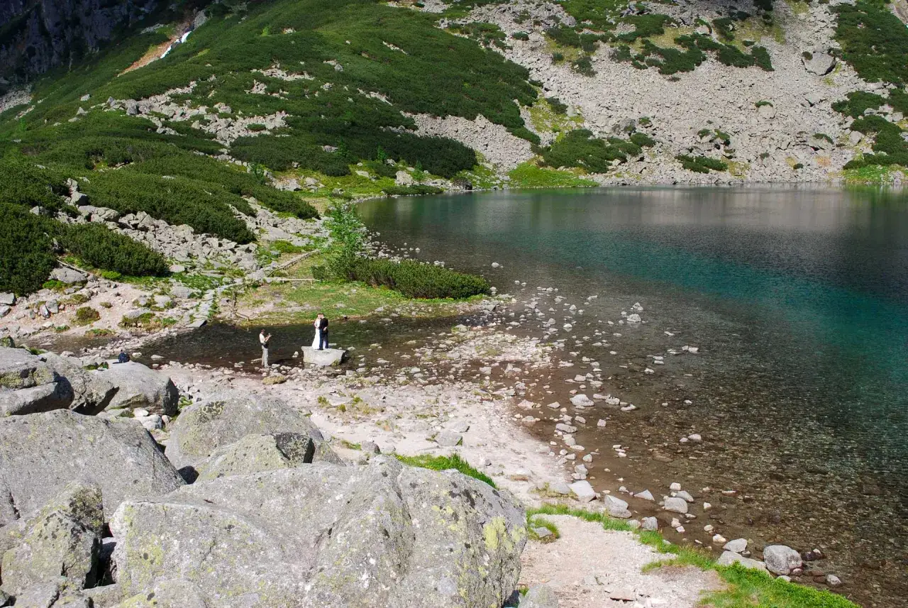 Para młoda pozuje do zdjęć nad stawem pod Rysami. W tle g&oacute;ry porośnięte kosodrzewiną.