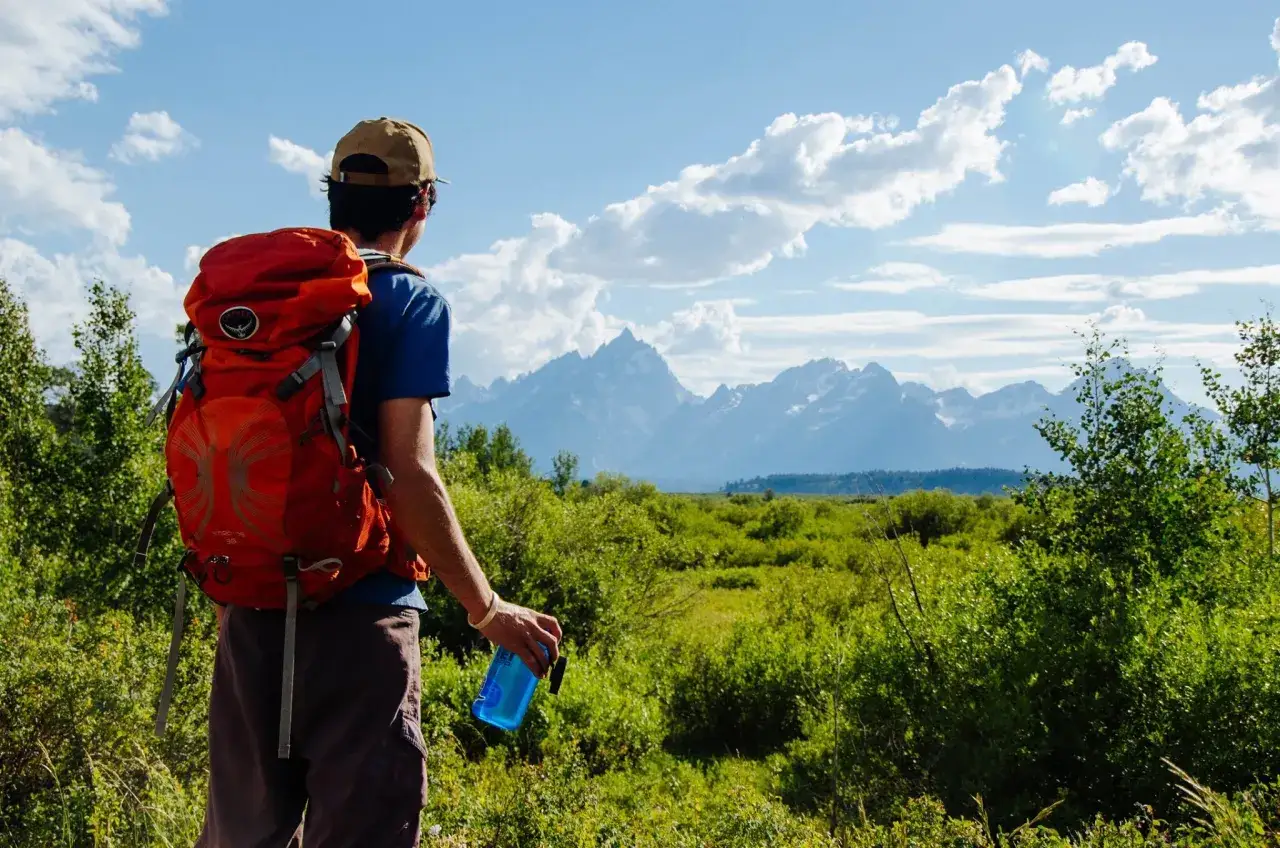 Mężczyzna z plecakiem podziwia góry. To właśnie jest hiking – przygoda na łonie natury.