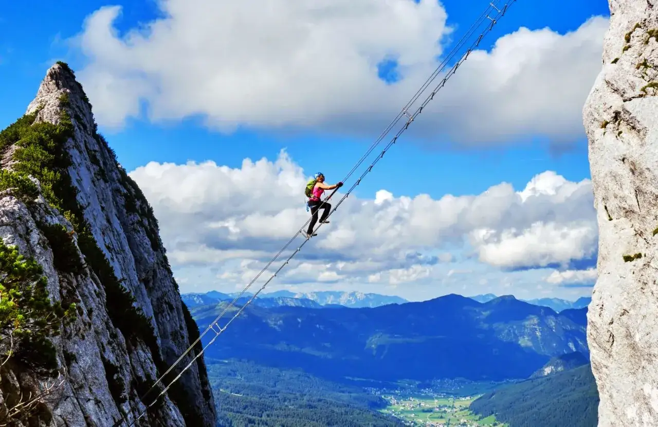 Osoba pokonuje most wiszący na via ferrata w Niemczech, podziwiając zapierającą dech w piersiach panoramę g&oacute;r.