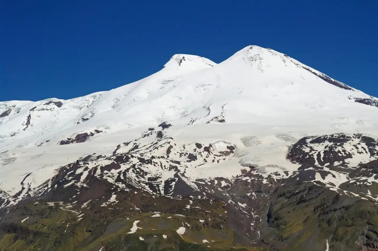 Pokryty śniegiem Elbrus, najwyższy szczyt Europy, majestatycznie wznosi się na tle błękitnego nieba.