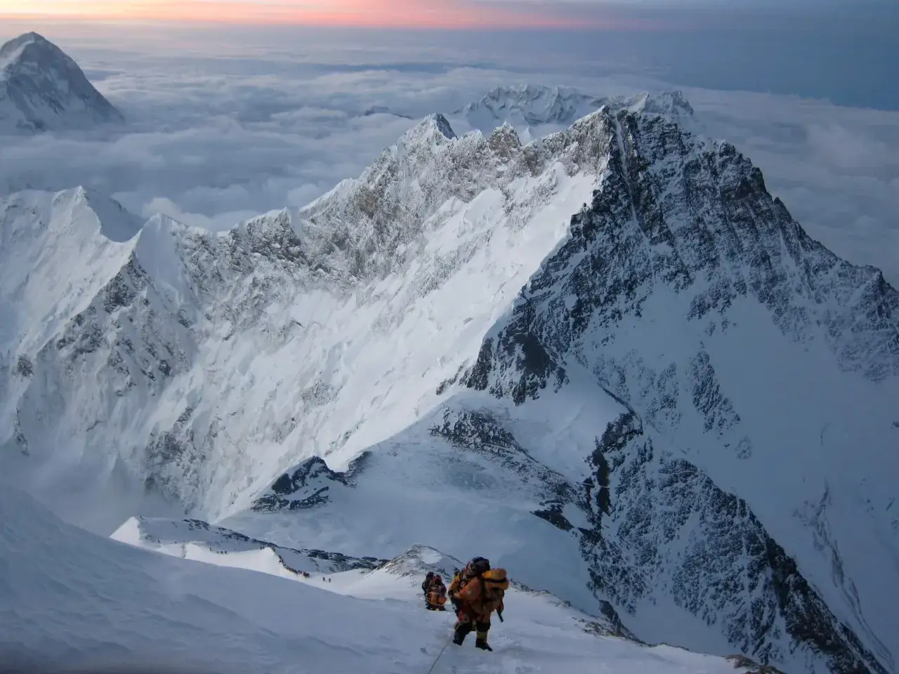 Wspinacze na trudnej mount everest trasie, pokonują ośnieżone zbocza w chmurach.