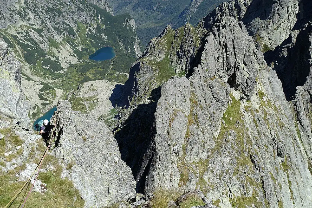 Wspinaczka na skalistą przełęcz w Tatrach Wysokich. Widok na turkusowe jezioro i strome zbocza.