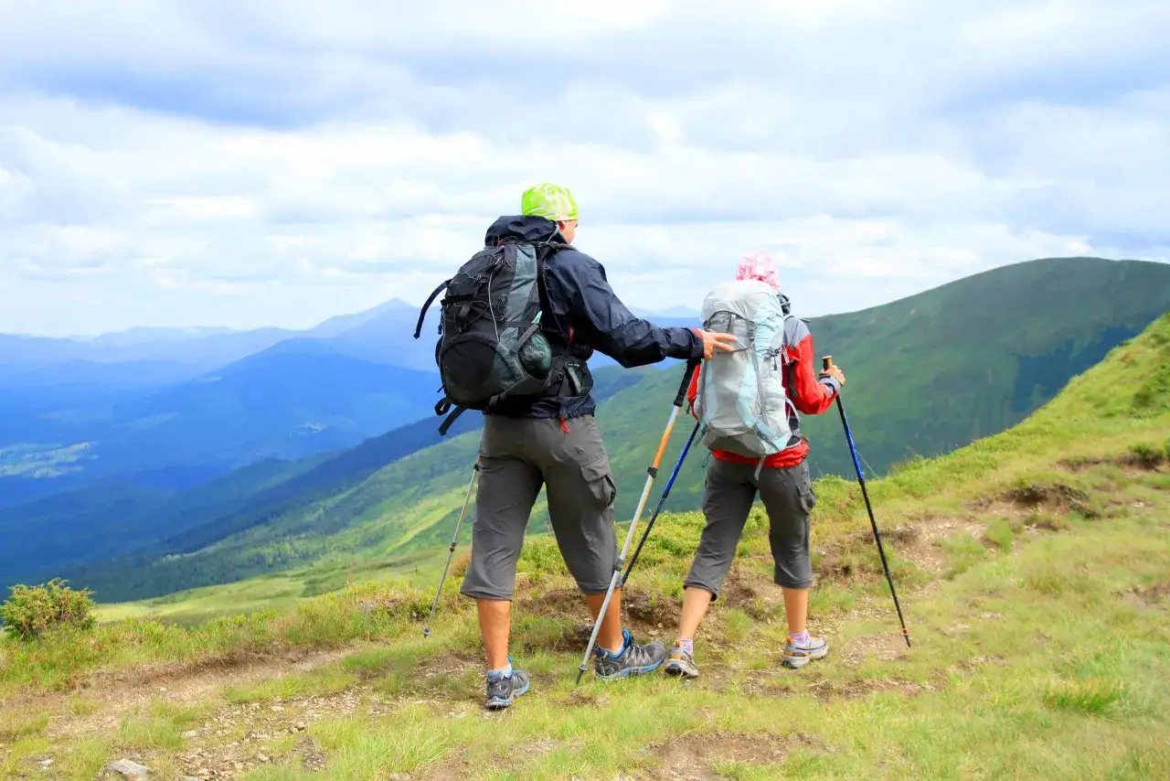 Para, jak chodzić z kijkami trekkingowymi, podziwia górski krajobraz.