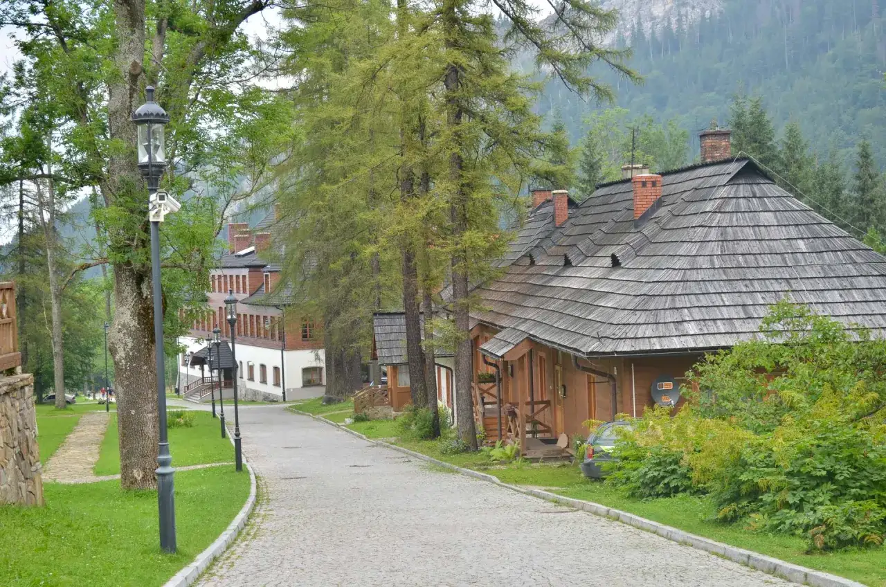 Droga do Kuźnic z Zakopanego prowadzi przez malowniczą okolicę z tradycyjną architekturą i zielenią.