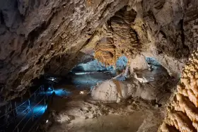 Wnętrze jaskiń w Zakopanem, z naciekami, stalaktytami i stalagmitami, oświetlone niebieskim światłem.