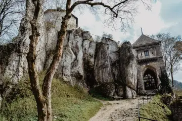Ojcowski Park Narodowy atrakcje: ruiny zamku na skale, kamienna wieża bramna i ścieżka wśród zieleni.